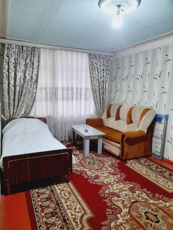 a bedroom with a bed and a couch and a rug at SAMIR GUEST HOUSE in Ganja