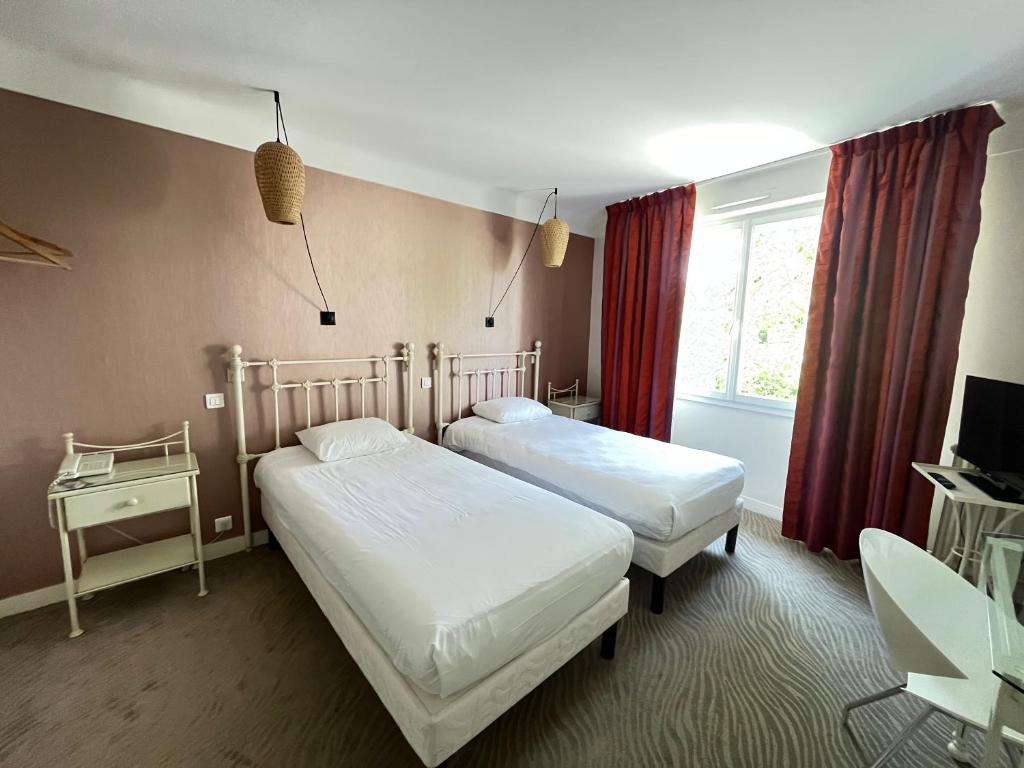 een slaapkamer met 2 bedden en een raam bij Grand Hôtel Niort Centre in Niort