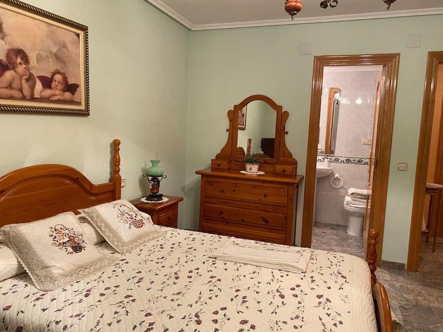 a bedroom with a bed and a dresser and a bathroom at Casa Rural María Josefa in Bronchales
