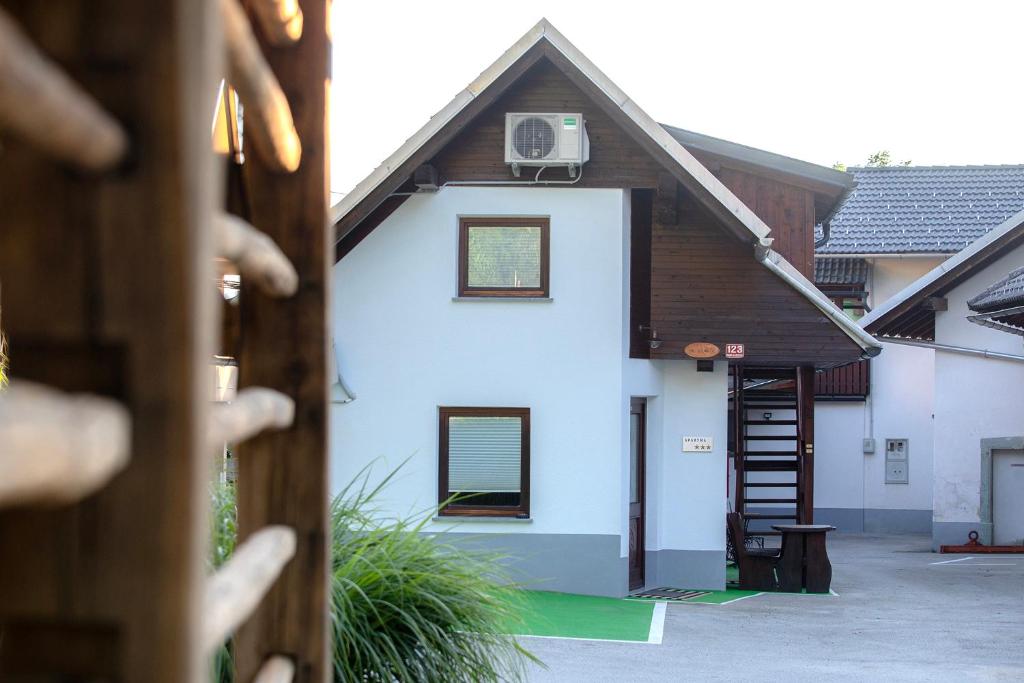 uma casa branca com um telhado de madeira e uma escada em Marjeta em Begunje na Gorenjskem