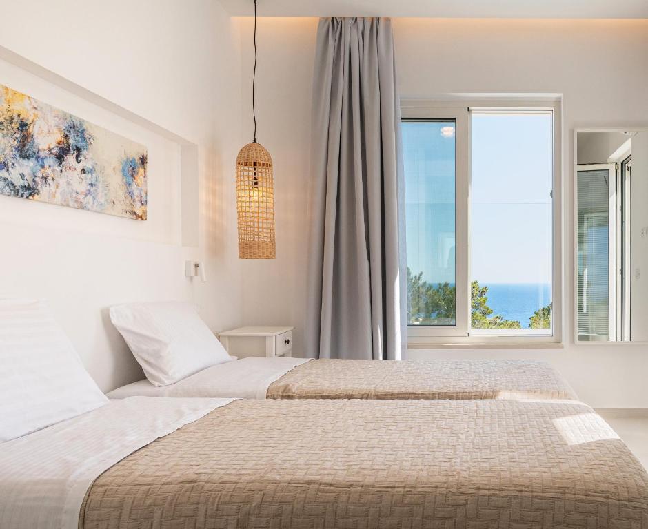 a bedroom with two beds and a large window at serene villas in Ierápetra