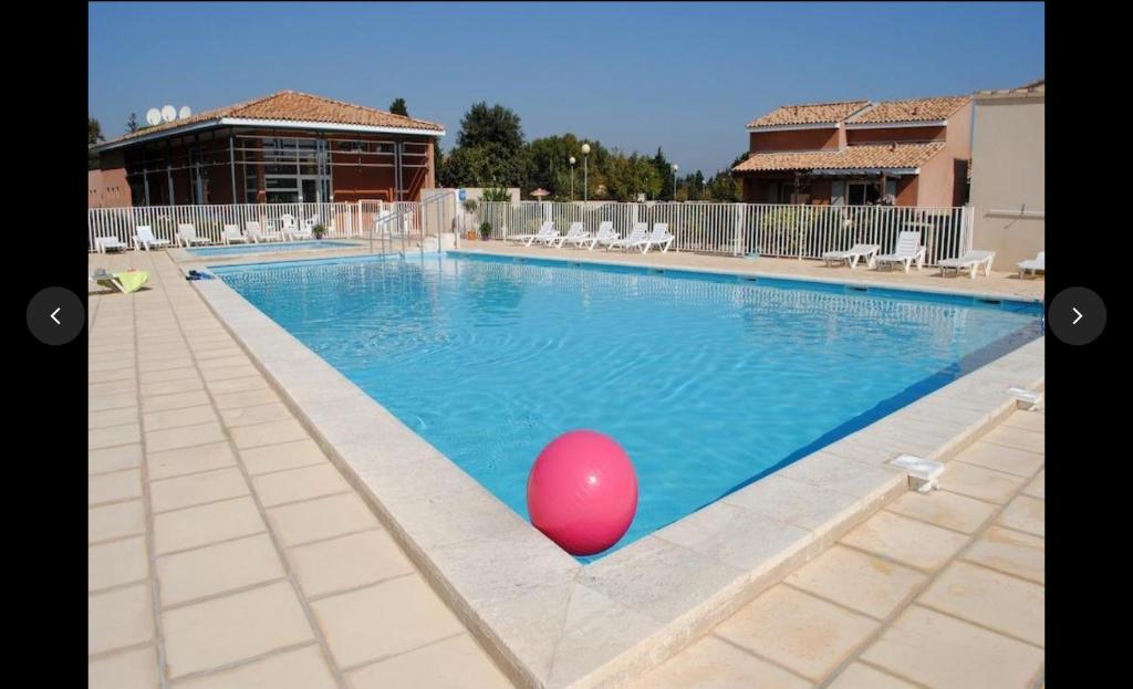 une grande piscine avec un ballon rouge au milieu dans l'établissement Maison plain pied avec climatisation dans une résidence privée avec piscine, à Saint-Saturnin-lès-Avignon