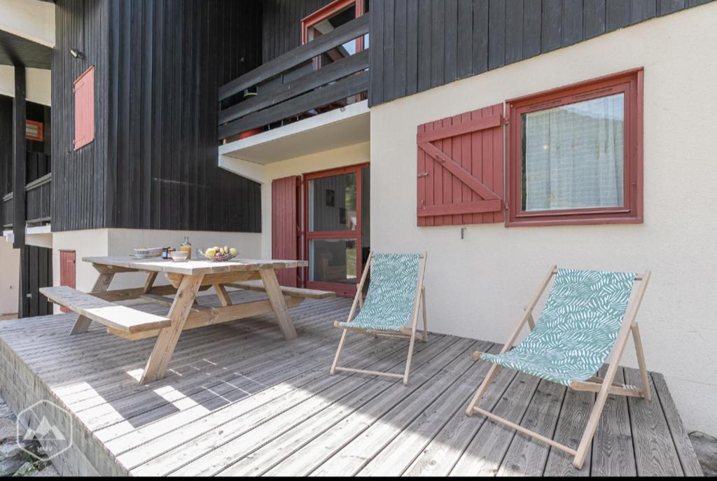 une table en bois et deux chaises sur une terrasse dans l'établissement La Norma en Terrasse, à Villarodin-Bourget