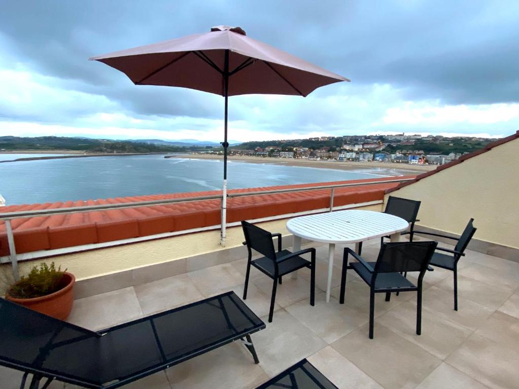 un patio con mesa, sillas y sombrilla en Playa de los Locos con Garaje, en Suances