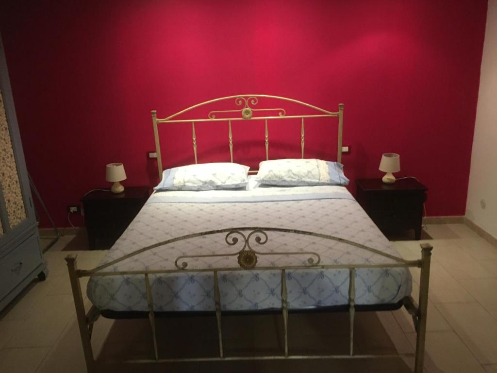 um quarto com uma cama com uma parede rosa em Casa Movida em Trapani