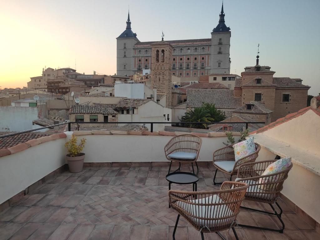 Un balcón con sillas y vista a una ciudad. en La Casa Toledana - patio y terraza con vistas, en Toledo