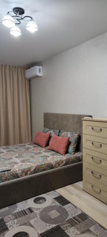a bedroom with a bed with two pillows and a dresser at Уютная 2 ком.квартира in Kostanay