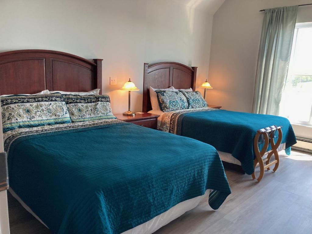 2 camas en una habitación de hotel con sábanas verdes en Lunenburg Arms Hotel, en Lunenburg
