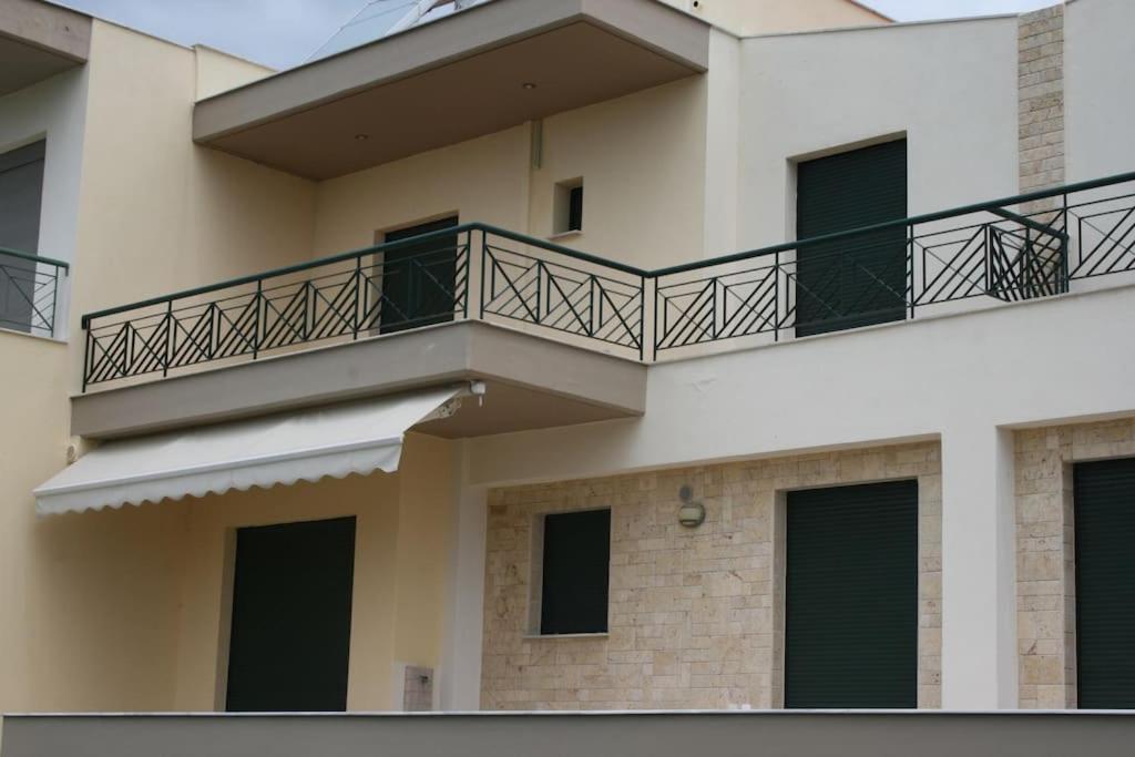 a building with a balcony with green doors at elgevacation villa 1 in Lagomandra