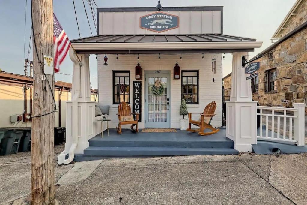 una pequeña casa blanca con porche y bandera en King Bed Bungalow Just Feet from Historic Main Street, en Blue Ridge