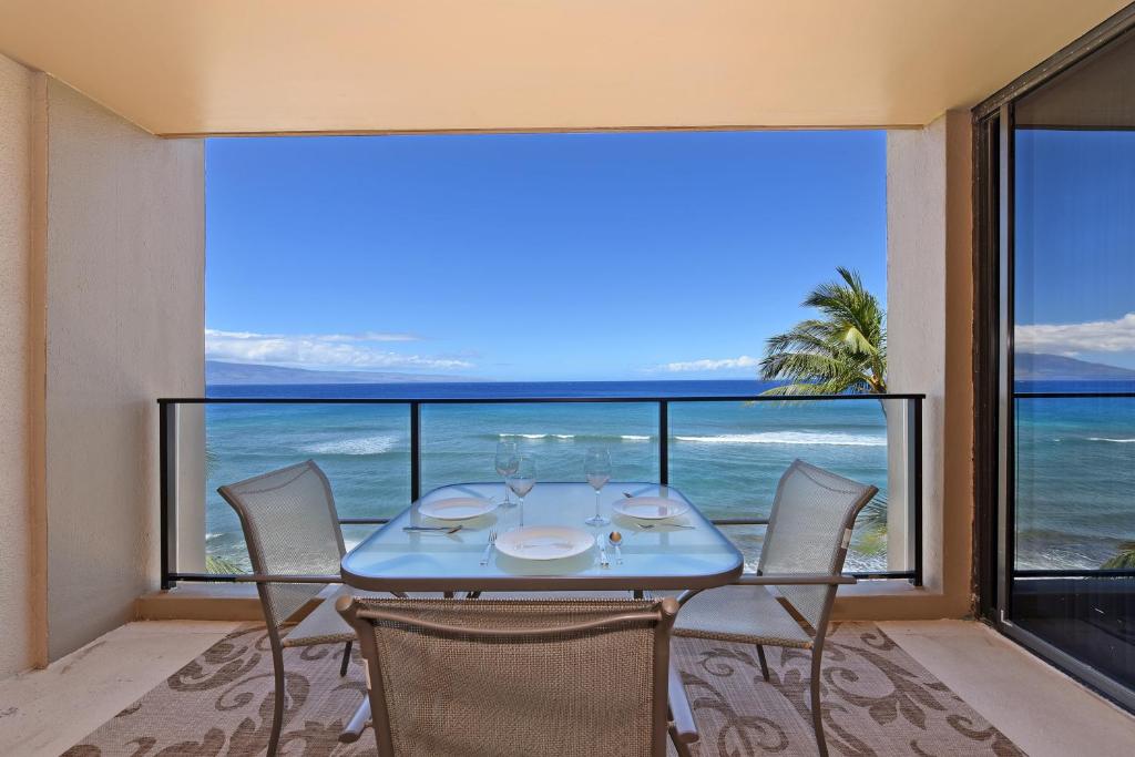a dining room with a table and chairs and a view of the ocean at Mahana Resort #518 in Kahana