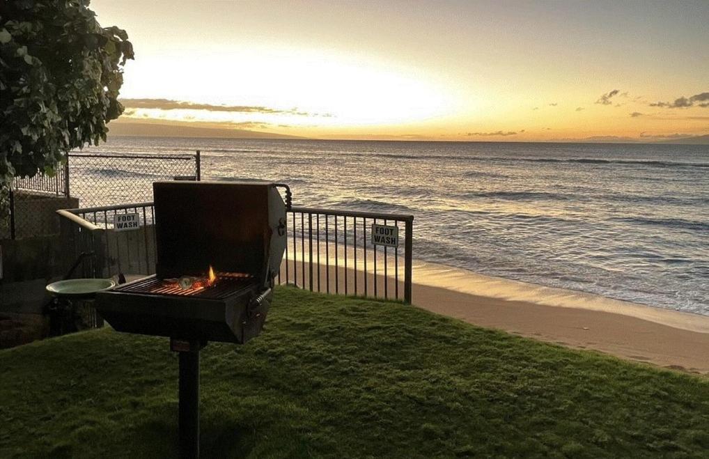 a barbecue grill sitting on the grass near the beach at Hale Mahina #B102 in Kahana