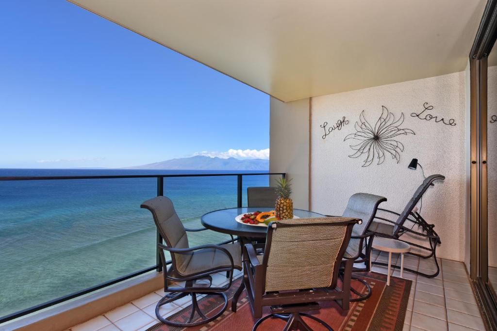 a balcony with a table and chairs and the ocean at Mahana Resort #1104 in Kahana