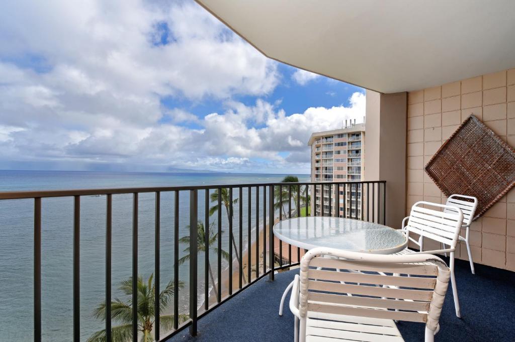 a balcony with a table and chairs and the ocean at Valley Isle #808 in Kahana