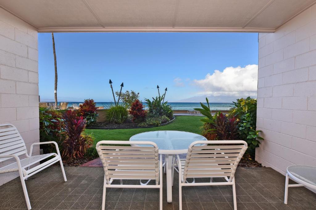 a table and chairs on a patio with a view of the ocean at Makani Sands #102 in Kahana