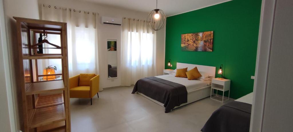 ein grünes Schlafzimmer mit einem Bett und einem Stuhl in der Unterkunft Manzoni 159 in Neapel