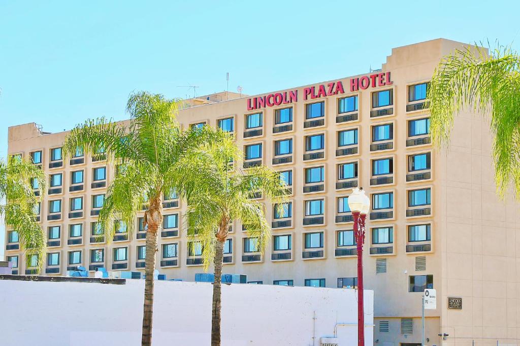 a hotel with palm trees in front of a building at Lincoln Hotel Monterey Park Los Angeles in Monterey Park