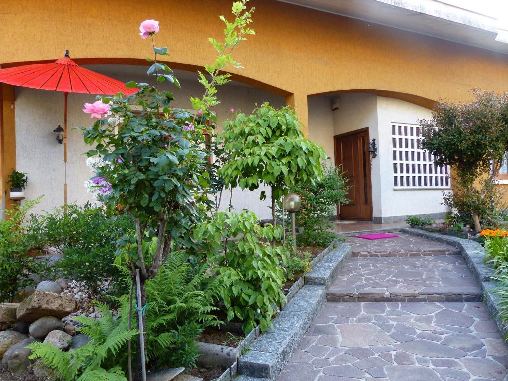 a garden with a pathway and an umbrella in front of a house at Cuscino e Caffé in Rescaldina