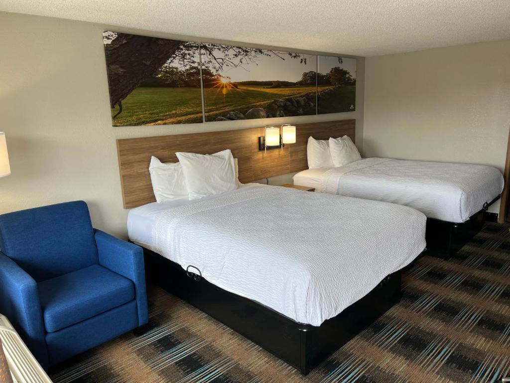 um quarto de hotel com duas camas e uma cadeira azul em Days-Inn by Wyndham Liverpool-Syracuse em Liverpool
