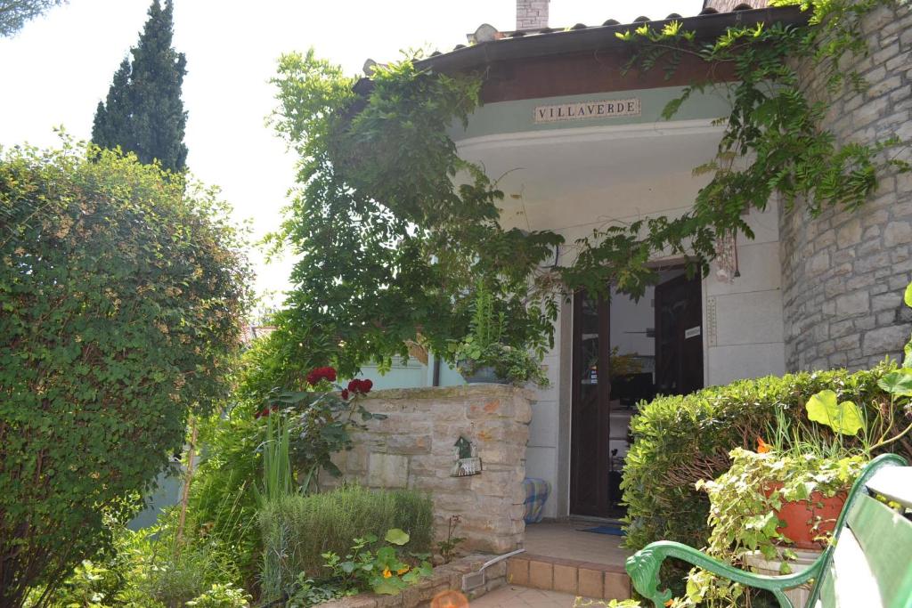 a house with a entrance to a yard with flowers at Villa Verde Apartments and Rooms in Premantura