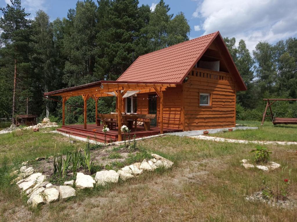 una cabaña de madera en un campo con árboles en Domek w lesie en Biłgoraj