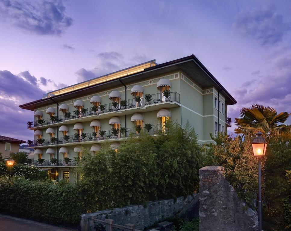 un gran edificio con balcones y luz de la calle en Palace Hotel San Pietro en Bardolino