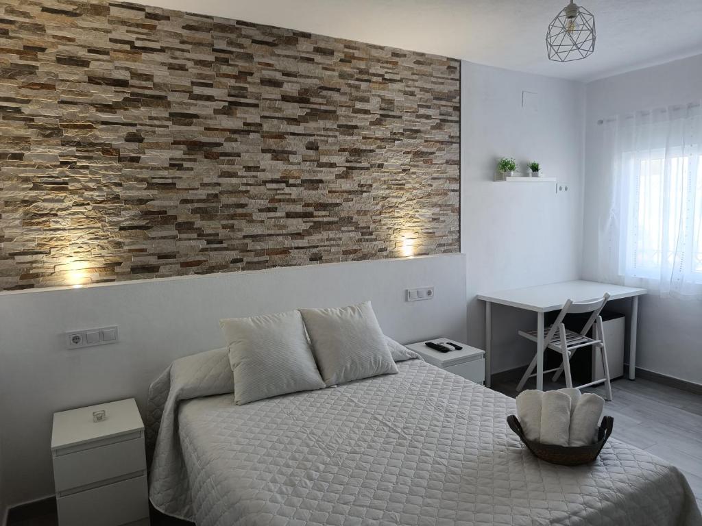 a bedroom with a bed and a brick wall at Alojamientos La Menúa in Los Badalejos