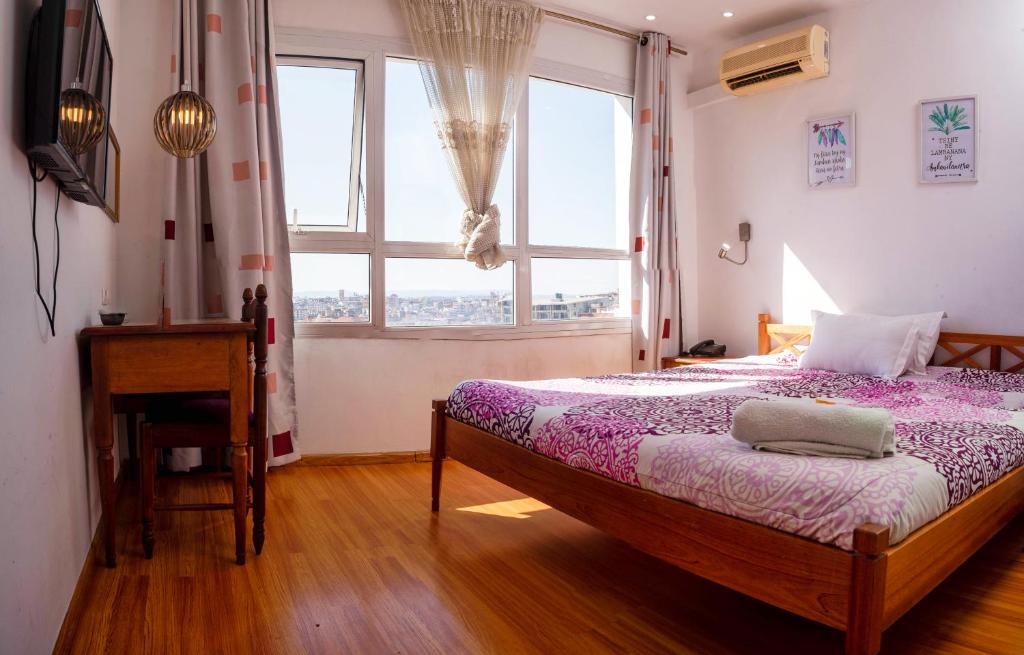 1 dormitorio con cama, ventana y escritorio en RADAMA Hotel, en Antananarivo