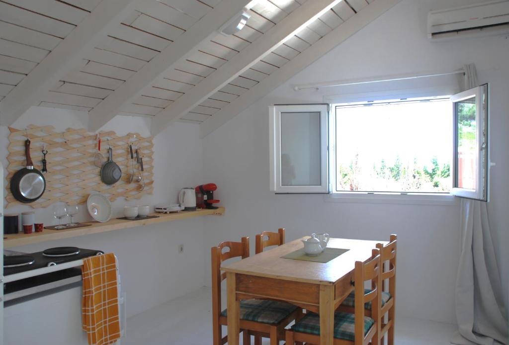 cocina blanca con mesa de madera y ventana en Katelios Farm House Loft, en Katelios