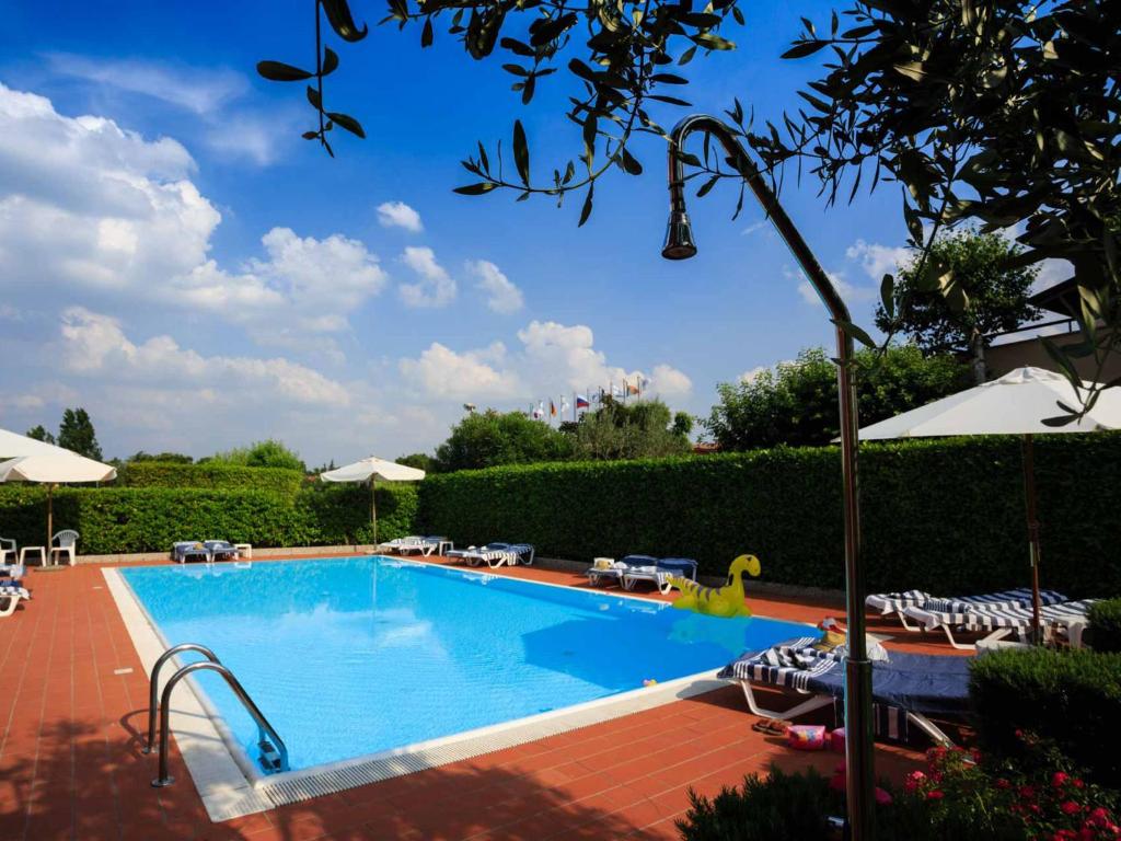 a large swimming pool with chairs and umbrellas at BellaSirmione Holiday Apartments in Sirmione