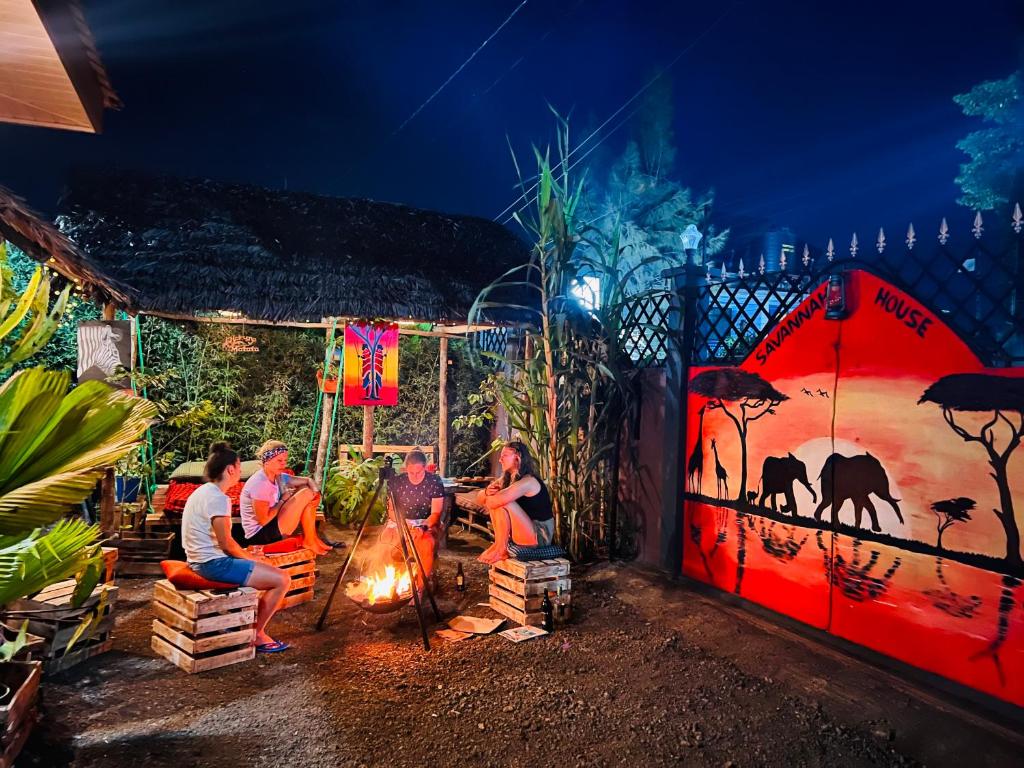 Un groupe de gens assis autour d'un feu la nuit dans l'établissement Savannah House, à Arusha