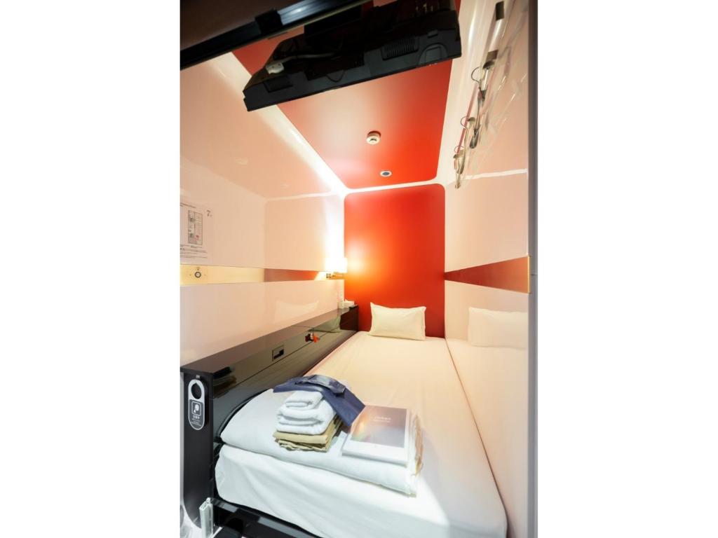金沢市にあるTorifito Hotel & Pod Kanazawa - Vacation STAY 88230vの小さなお部屋で、ベッド1台(電話付)が備わります。