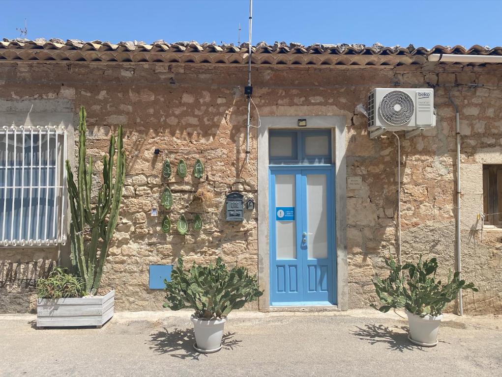 a blue door on a stone building with two plants at Mareantico Shabby Apartment in Sampieri