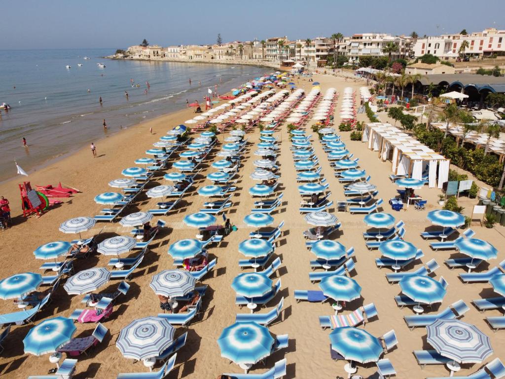 plaża pełna niebiesko-białych parasoli w obiekcie Mareantico Shabby Apartment w mieście Sampieri