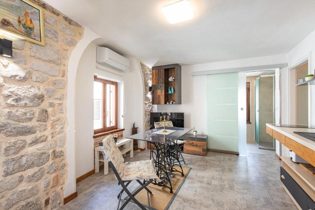 a kitchen and dining room with a stone wall at Apartman Stefani in Krk