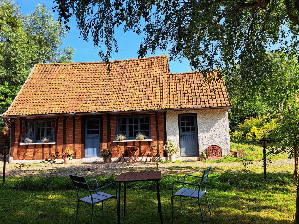 ein Haus mit einem Tisch und Stühlen davor in der Unterkunft Le Bois d'Albran in La Calotterie