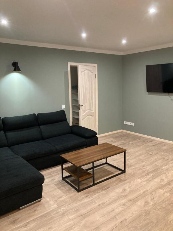 a living room with a black couch and a coffee table at Grīzupes apart in Liepāja
