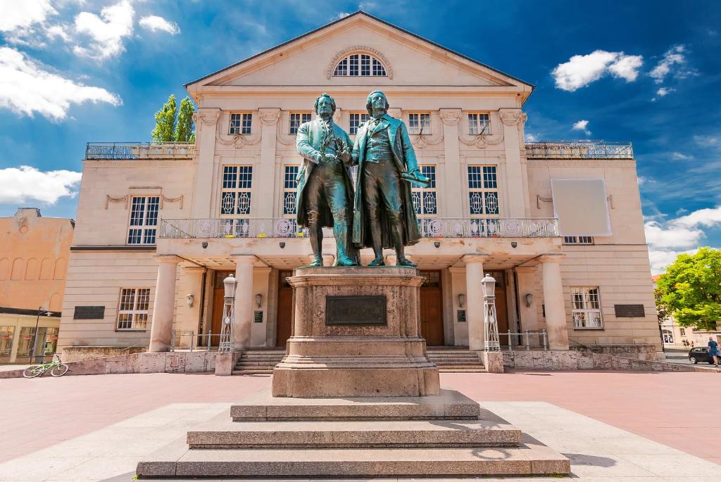 Una statua di due uomini davanti a un edificio di Cityappartements Weimar Bauhaus a Weimar