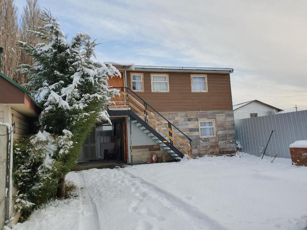 a house with a wooden staircase in the snow at Departamento Kran in Punta Arenas