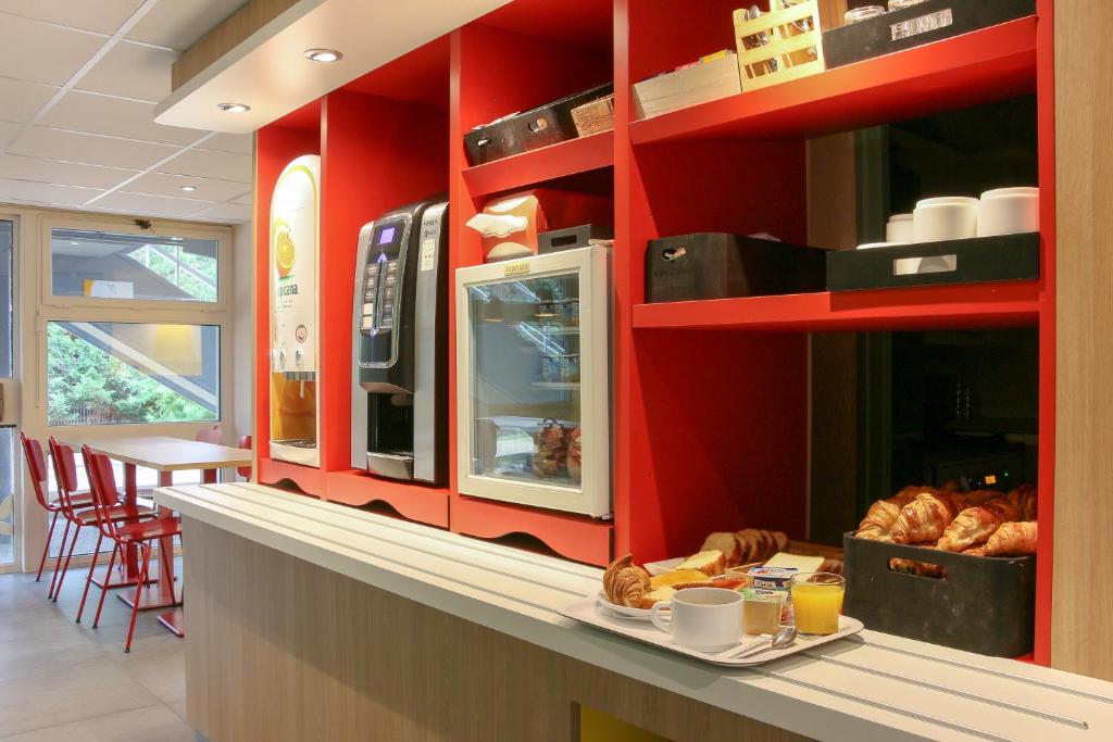 - une cuisine avec des murs rouges et un comptoir avec du pain dans l'établissement Premiere Classe Marseille Vitrolles Aéroport, à Vitrolles