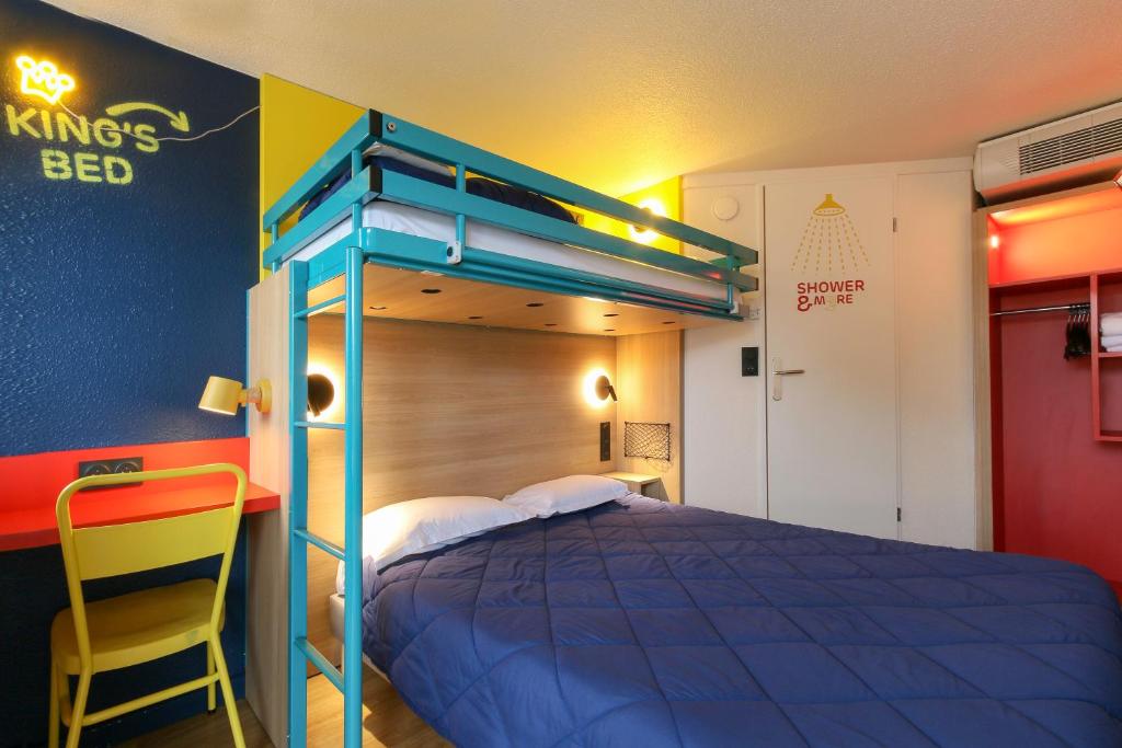 - une chambre avec un lit bleu et une chaise jaune dans l'établissement Premiere Classe Marseille Vitrolles Aéroport, à Vitrolles