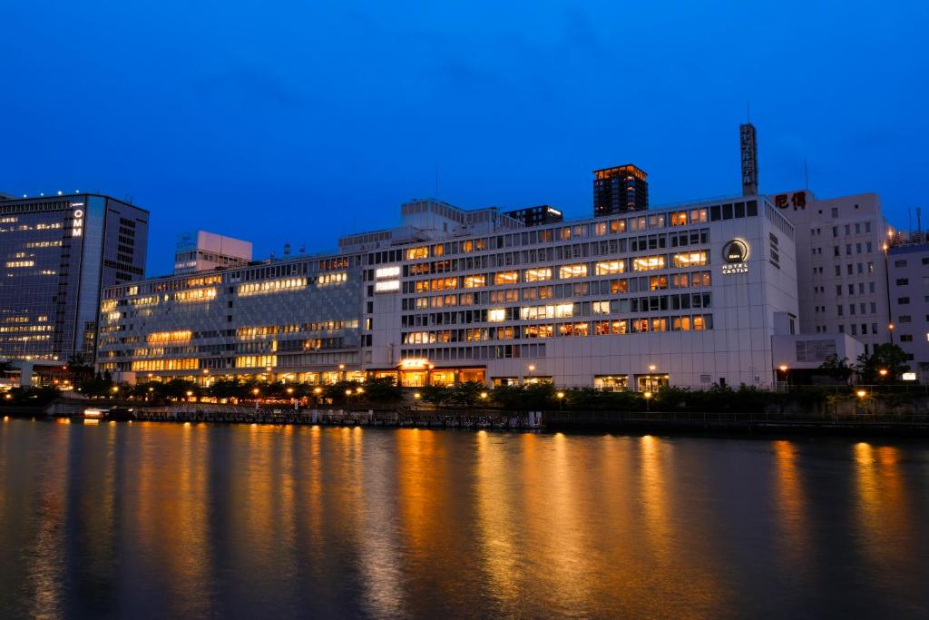 a lit up building next to a river at night at Hotel Osaka Castle in Osaka