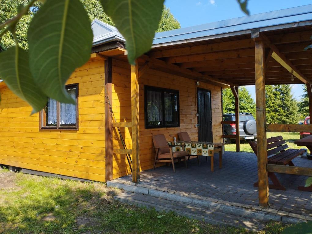 mała drewniana kabina z patio i stołem w obiekcie Nad Stawami w mieście Narewka