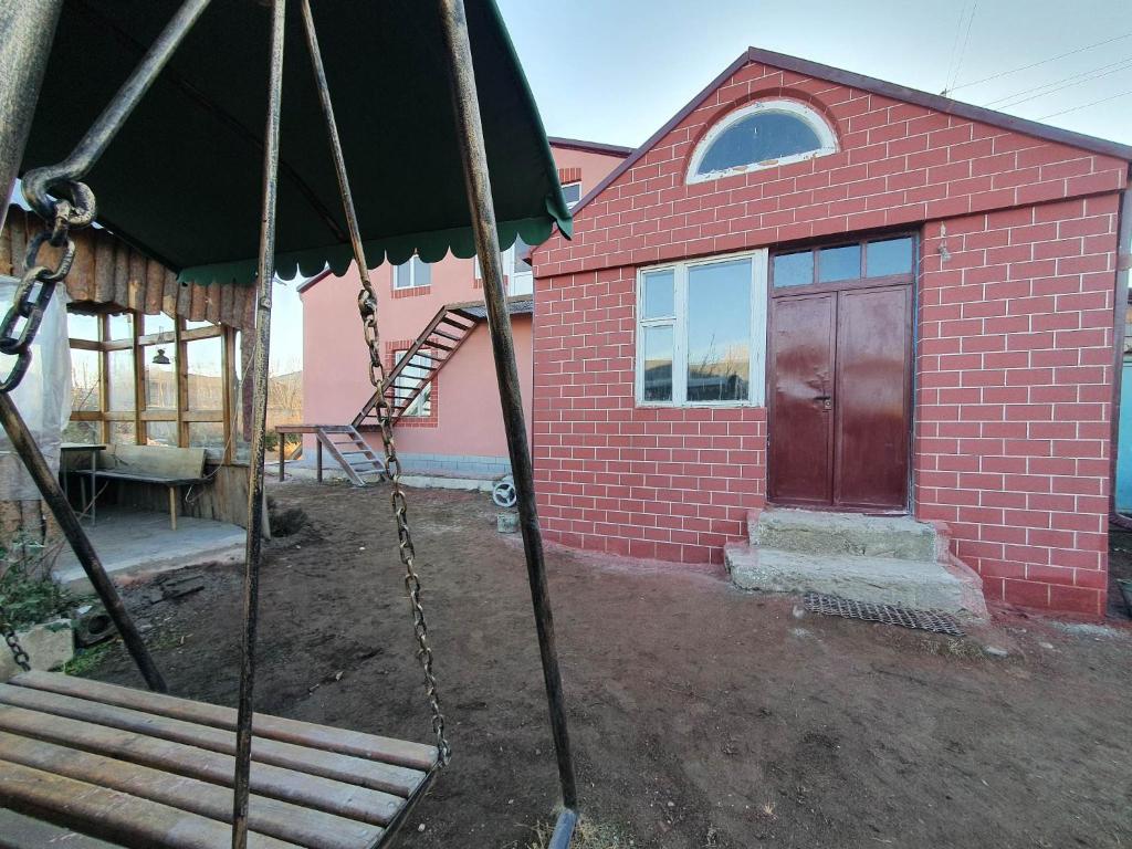 una casa de ladrillo rojo con un columpio delante de ella en Moreni Guest House en Gavarr