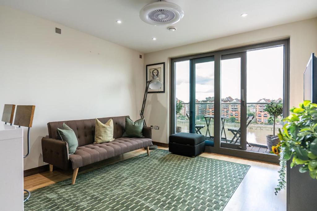 a living room with a couch and a large window at Livestay-Stunning Apartment With Private Balcony & River Views in London