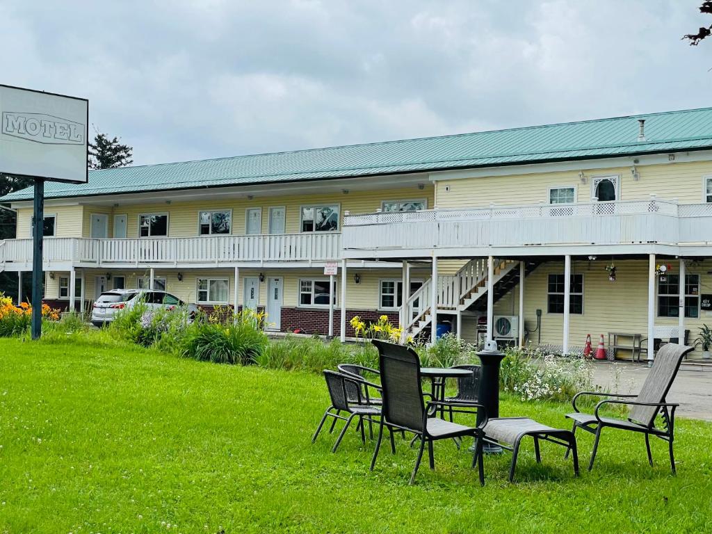 un hôtel avec des chaises et une table dans l'herbe dans l'établissement Scenic Motel Moncton, à Moncton