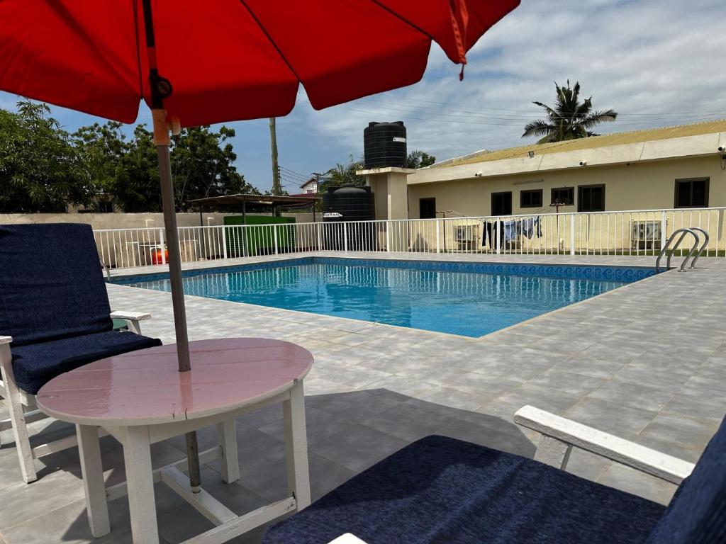 a table with an umbrella next to a swimming pool at Exclusive Holiday Villa with Pool in Accra in Accra