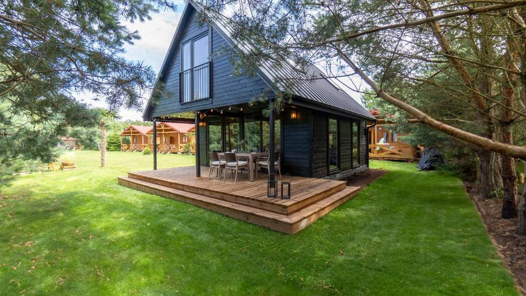 a small house with a wooden deck in a yard at Kompleks Wypoczynkowy Bryza I in Lubiatowo