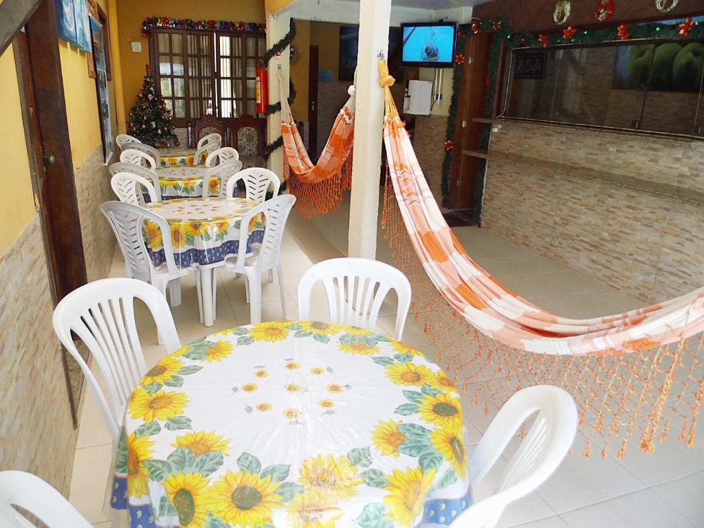 a patio with a table and chairs and hammocks at Casa e Praia Hospedaria in Arraial do Cabo