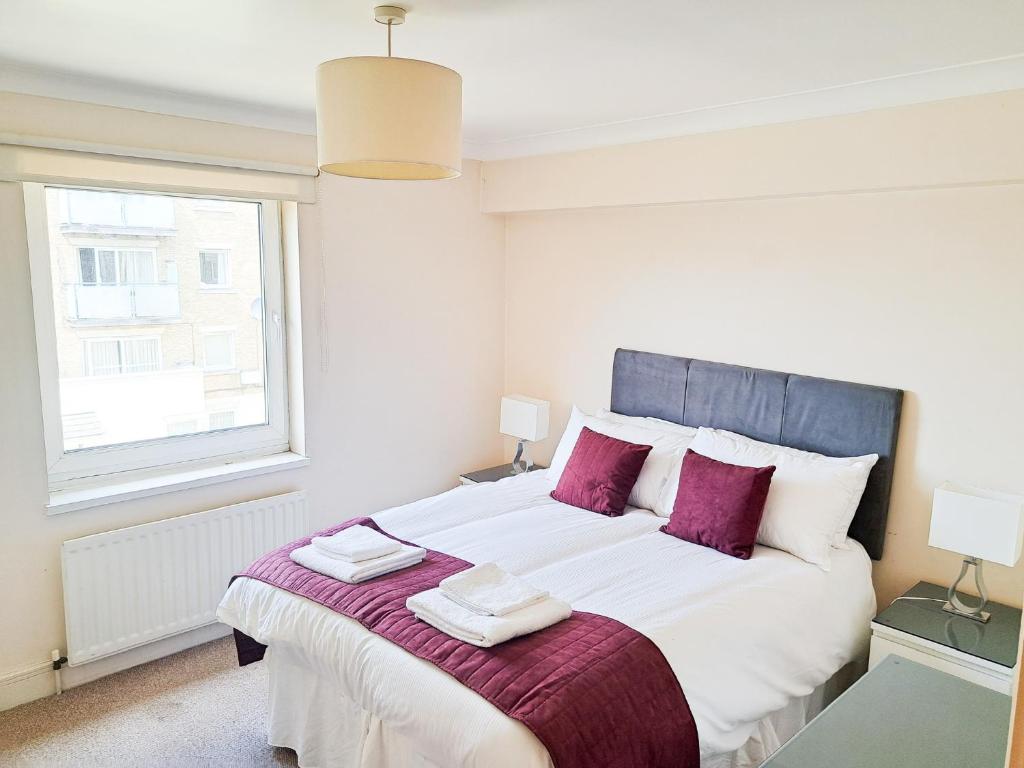 a bedroom with a large white bed with purple pillows at Wimbledon Apartment in London